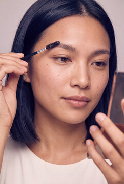 Closeup woman grooming eyebrows with spoolie brush for makeup routine and natural beauty tutorial background