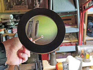 Obraz premium Magnifying glass inspecting a wood screw in a workshop. Close-up of hardware under magnification, concept of precision, quality control, repair, craftsmanship and DIY projects. 