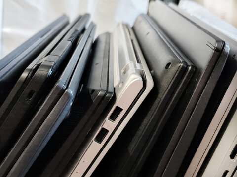 Several modern laptop computers stacked side by side showing USB ports and aluminum chassis. Technology comparison, computer hardware, office equipment and digital devices concept.
