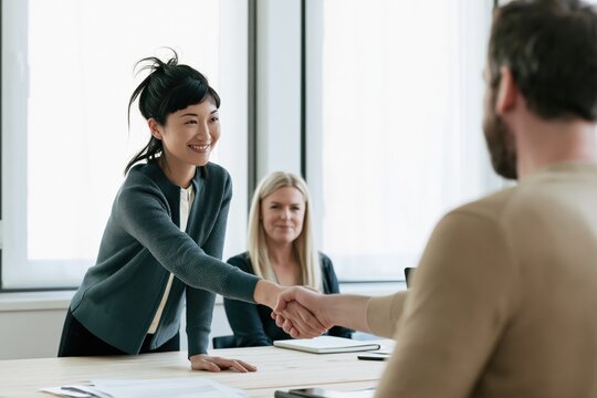 Businesswoman shaking hands with client after successful meeting, closing a deal and building professional business partnership