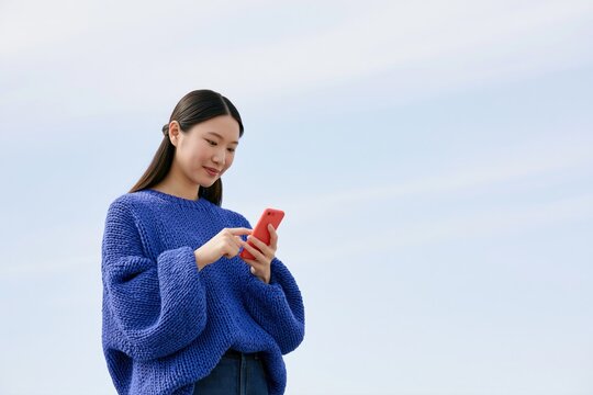 Young woman using smartphone outdoors, enjoying modern digital lifestyle, social media, online communication and everyday connectivity
