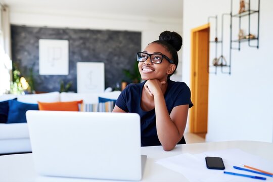 Smiling businesswoman working on laptop in modern home office, planning projects and enjoying flexible remote work