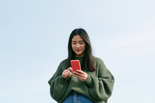 Young woman using smartphone outdoors for social media, mobile communication, online shopping and digital lifestyle