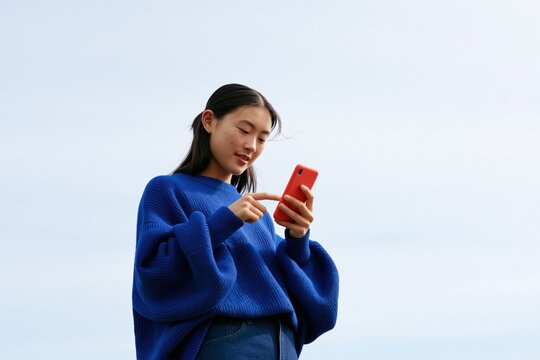 Young woman using smartphone outdoors for mobile banking, social media, online communication and everyday digital services