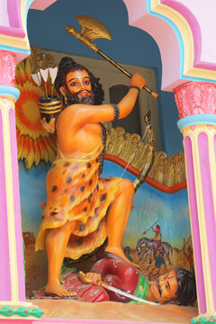 Full length vertical view of a colorful Hindu god Parashurama statue holding an axe in a temple.