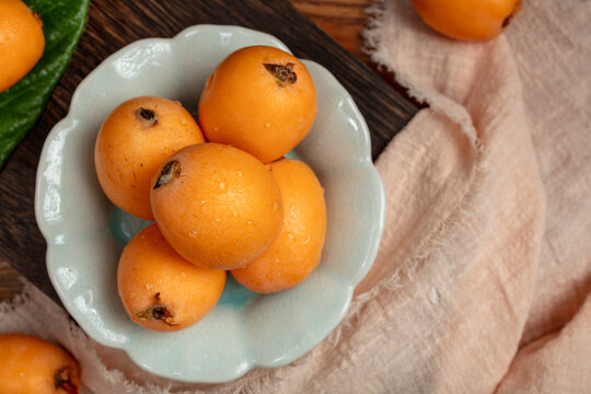 Fresh Loquats in a Ceramic Bowl on Rustic Table