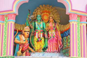 Obraz premium Vibrant colorful statues of Hindu deities Rama, Sita, and Hanuman inside a traditional temple wall niche.