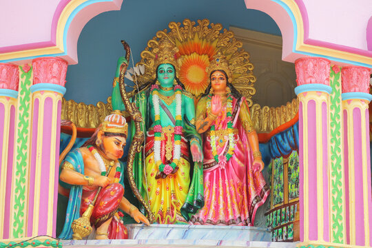 Vibrant colorful statues of Hindu deities Rama, Sita, and Hanuman inside a traditional temple wall niche.
