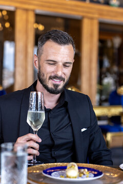 Handsome man in jacket holding glass of champagne during fine dining dinner