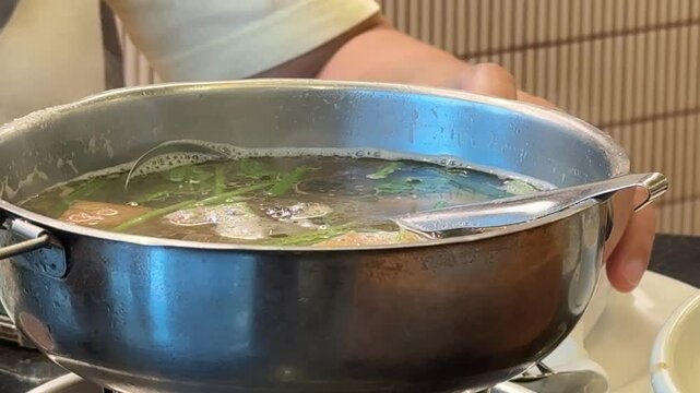 Horizontal 4K video of boiling fish head taro hot pot with steam rising from the metal burner bowl. 