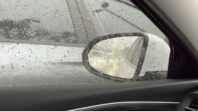 Horizontal 4K video focusing on left side mirror covered in heavy rain drops reflecting stuck traffic queue. 