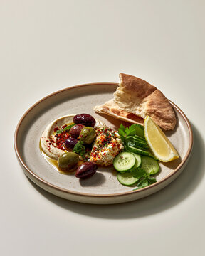 Eastern Mediterranean mezze plate with marinated olives soft cheese cucumber herbs and torn flat bread showcasing quiet luxury dining