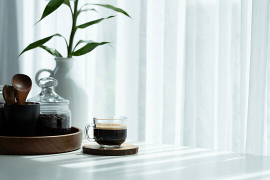 Coffee glass cup and roasted coffee beans in a glass jar on a white table