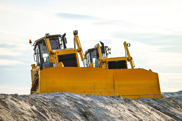Modern bulldozer working on sand at a quarry or construction site. Heavy machinery moving and leveling sand during earthmoving and industrial operations. © senssnow