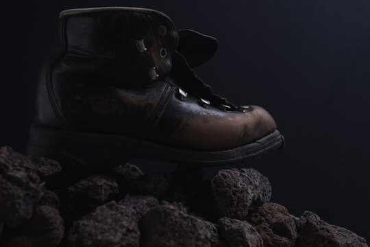 old leather hiking boot standing on rock stones