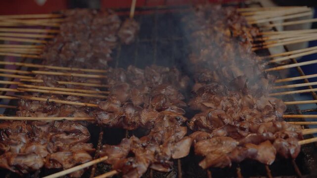 Traditional thai street food grilled chicken skewers with glistening sauce close up.