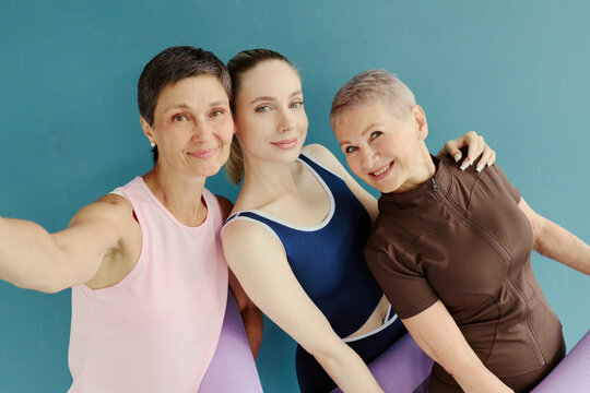 Portrait of three Caucasian women of different generations taking selfie after yoga class, representing active lifestyle and wellness, ideal for fitness marketing campaigns