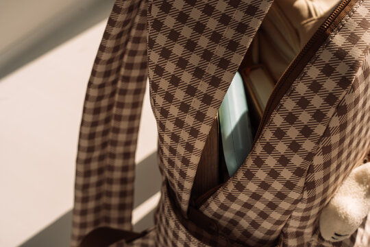 Open checkered backpack with school supplies in dramatic sunlight, back to school concept.