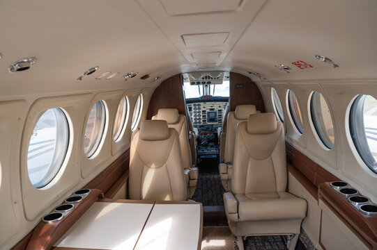 Nairobi, Nairobi County, Kenya - 23 December 2023: View of the interior of a private aircraft cabin featuring beige leather seats, a small table, and a view into the cockpit.