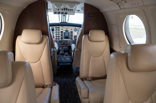 Nairobi, Nairobi County, Kenya - 23 December 2023: View of the interior of a small aircraft cabin with beige leather seats and a view into the cockpit.