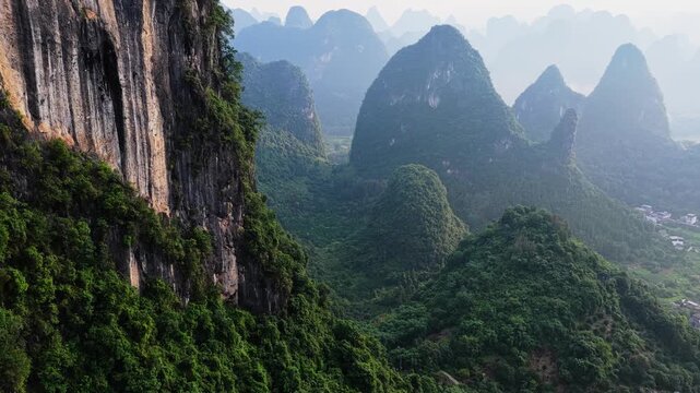 Aerial view of karst mountains with lush greenery and steep rock faces in Yangshuo County, Guilin, Guangxi, China.
