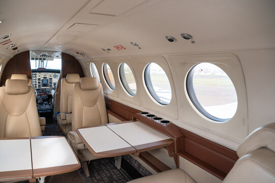 Nairobi, Nairobi County, Kenya - 23 December 2023: View of the interior of a private aircraft featuring beige leather seats, tables, and circular windows.