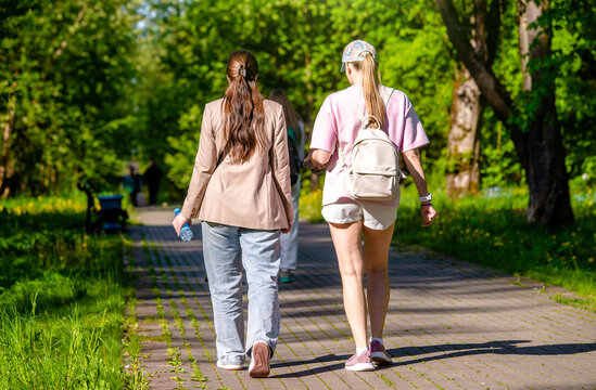 Two girlfriends walk along a path in the Park
