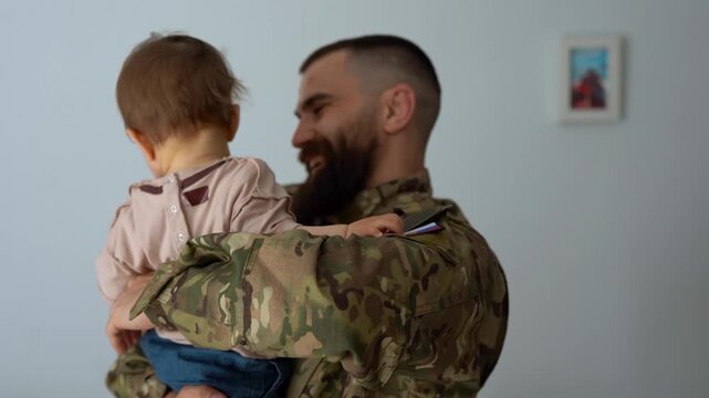Russian male soldier in military uniform returning home to family - Father hugging baby son - Homecoming, happiness and love concept