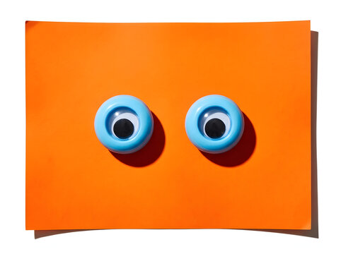 Two blue googly eyes on orange paper background