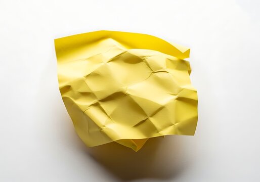 A crumpled yellow piece of paper on a white surface