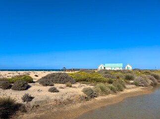 View over dunes and brackish land to white turquoise beach huts at the Playa de Camposot, Chiclana de la Frontera, San Fernando and Cadiz, Andalusia, Spain © keBu.Medien
