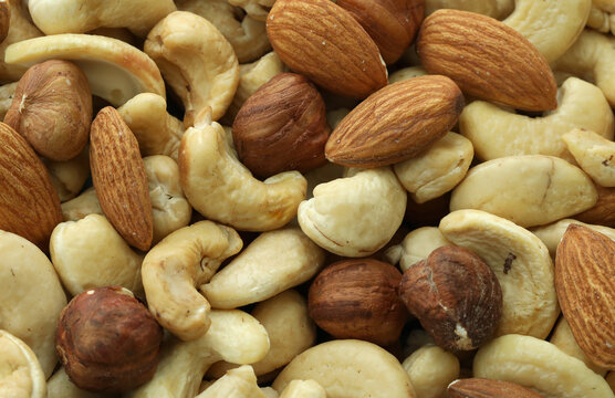 Detailed view on almond and cashew nuts in big pile on table close up