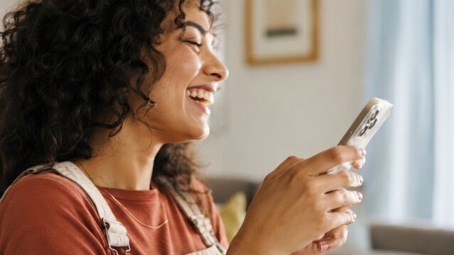 Smiling young woman enjoying social media on her smartphone at home.