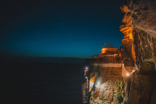 Cala en Porter, Spain - 12 May 2026: View of Cova d'en Xoroi illuminated at night, built into the cliffside overlooking the Mediterranean Sea.