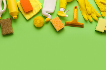 Fototapeta premium Assortment of yellow and orange Cleaning supplies and products arranged on a bright green background with copy space