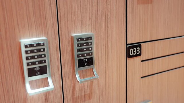 Close up panning shot moving from left to right capturing an electronic digital combination lock on a modern locker door inside a fitness gym changing room under bright interior lighting