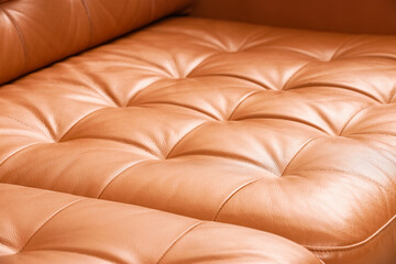 Fototapeta premium Close up of tufted brown leather upholstery texture on a modern sofa or armchair, furniture design and interior decor, the close up detail highlights the soft