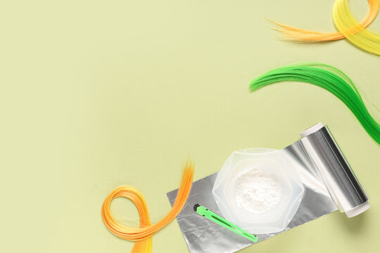 Hair dyeing tools with colorful hair strands and foil on a light green background, beauty and salon