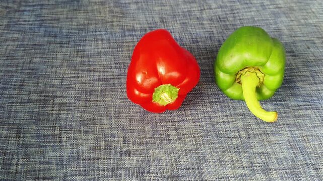 Two raw green and red color bell pepper, paprika or peperone fruit isolated on blue table with copy space. Vibrant and colorful variety of colours in capsicum vegetable concept. Closeup top view.
