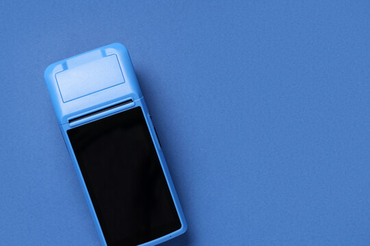 Payment terminal on blue background, top view