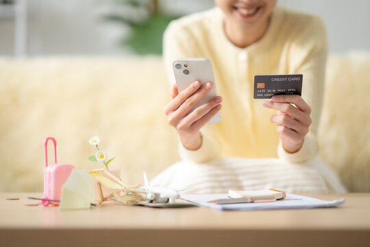 Asian woman paying with credit card on smartphone, buying travel insurance online, travel booking, vacation expenses, digital payment, trip protection, tourism concept.