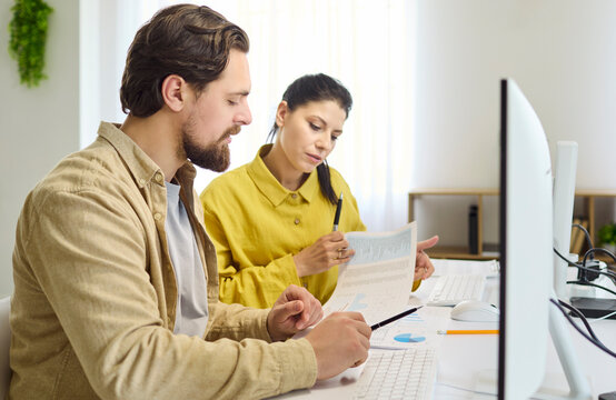 Couple planning budget finance analysis with documents. A man and woman review reports beside a computer, note expenses, and align goals with teamwork. Strong concept of household finances.