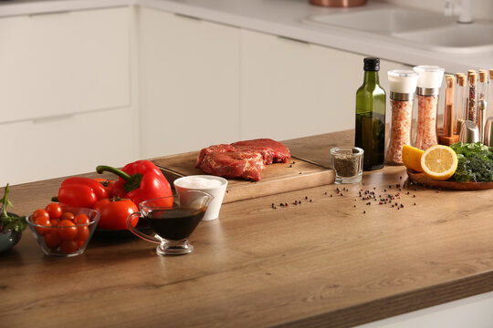 Raw meat with ingredients on table in kitchen