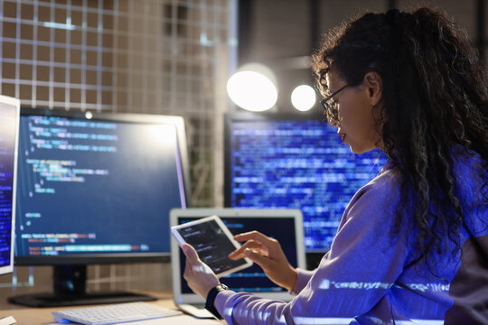 Female programmer with tablet computer working in office at night
