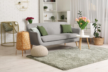 Stylish interior of living room with comfortable sofa, table and flowers © Pixel-Shot