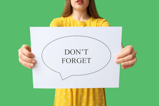 Young woman holding speech bubble with text DONT FORGET on green background. Reminder concept