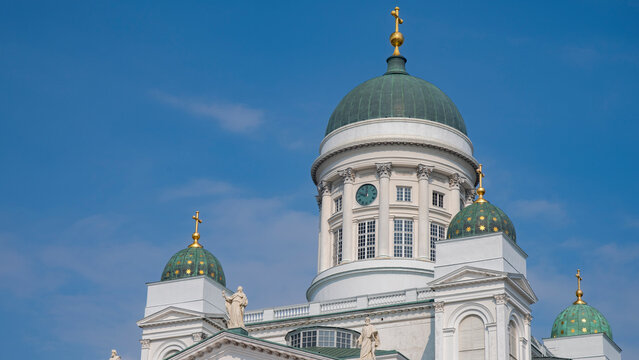 Close up of Helsinki Cathedral green domes with clock and blue sky copy space