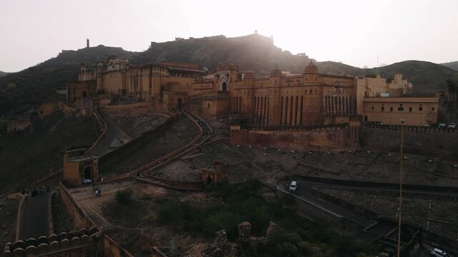 Aerial view of the amber fort in jaipur with the sun setting behind the aravalli hills in rajasthan, india