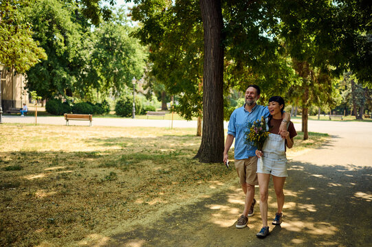 Happy Couple Walking in City Park With Bouquet &mdash; Asian Woman and Partner Enjoying Summer Stroll