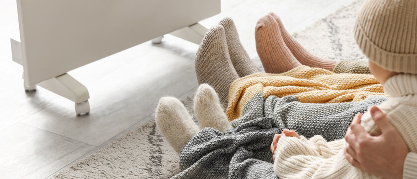 Family feet in warm socks and blankets by a heater, cozy Home comfort and winter heating